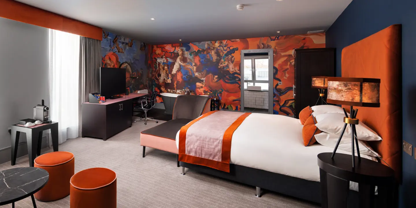Bedroom featuring a comfortable bed, sofa, desk and bath tub.