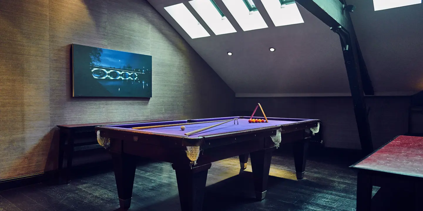 A pool table in a dark room.