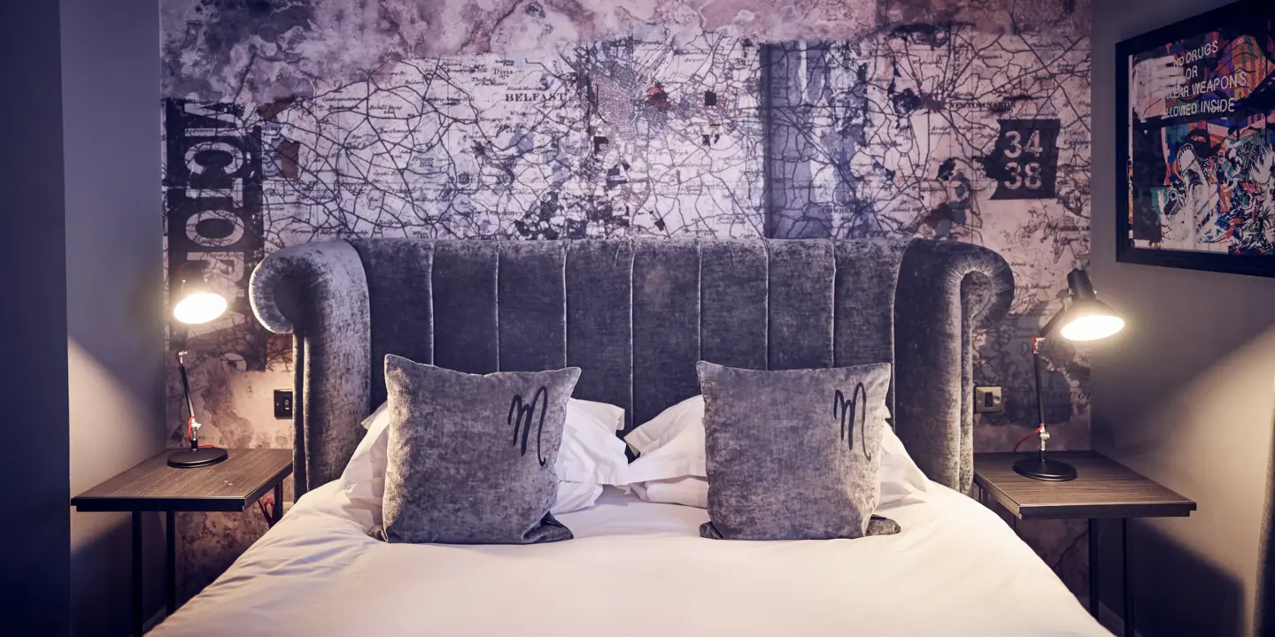 A bed featuring a grey velvet headboard adorned with plush pillows.