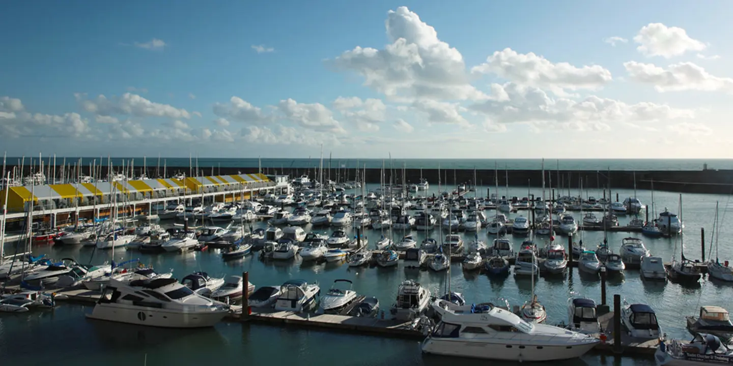 Brighton Marina from a high angle featuring sail boats and yachts moored and the famous yellow and white striped jetty canopy to the left of the image