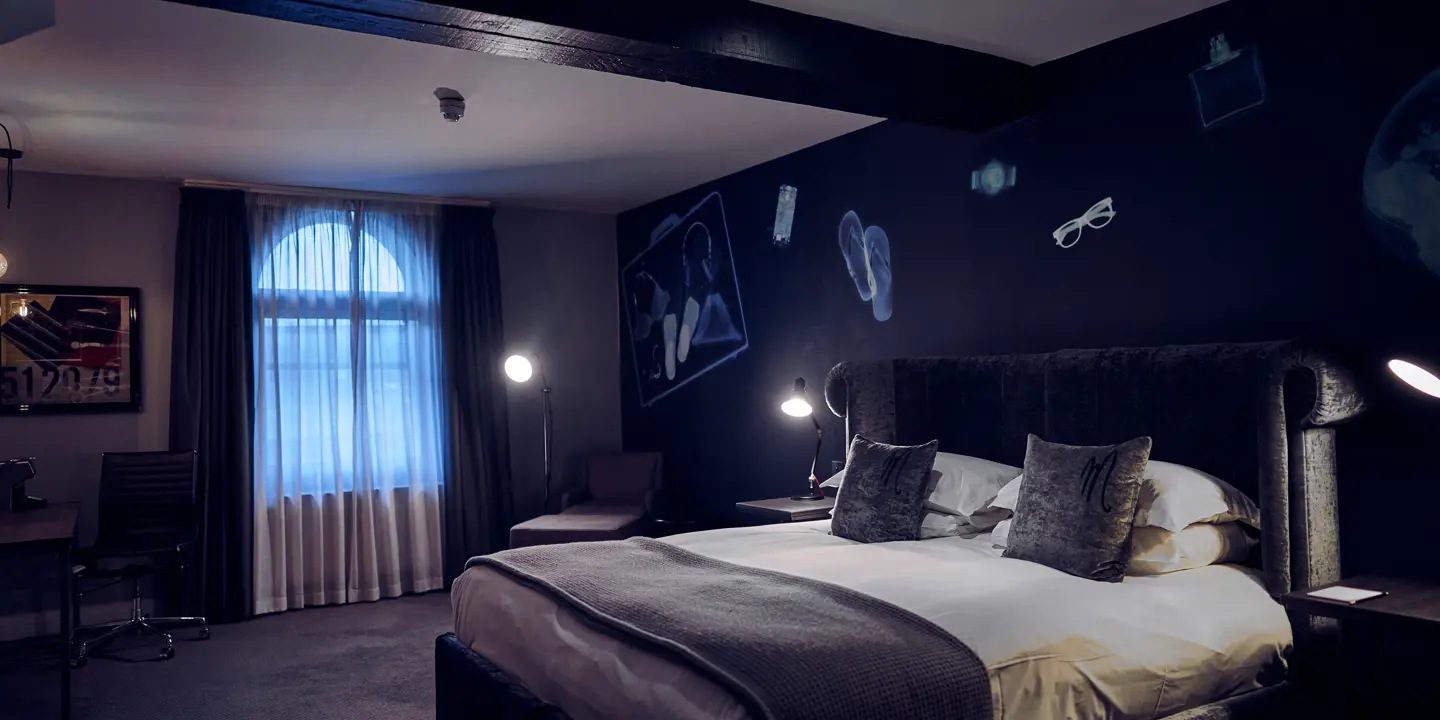 Bedroom featuring a grey velvet bed with black bedside tables.
