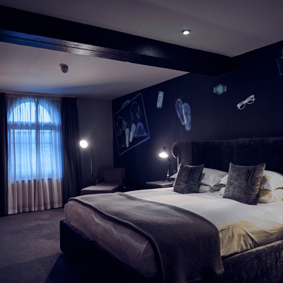 Bedroom featuring a grey velvet bed with black bedside tables.