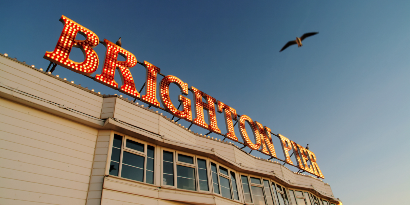 The famous Brighton Pier sign lit up with a seagull flying overhead