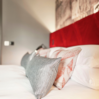 A bed featuring a vibrant red headboard and matching pillows.