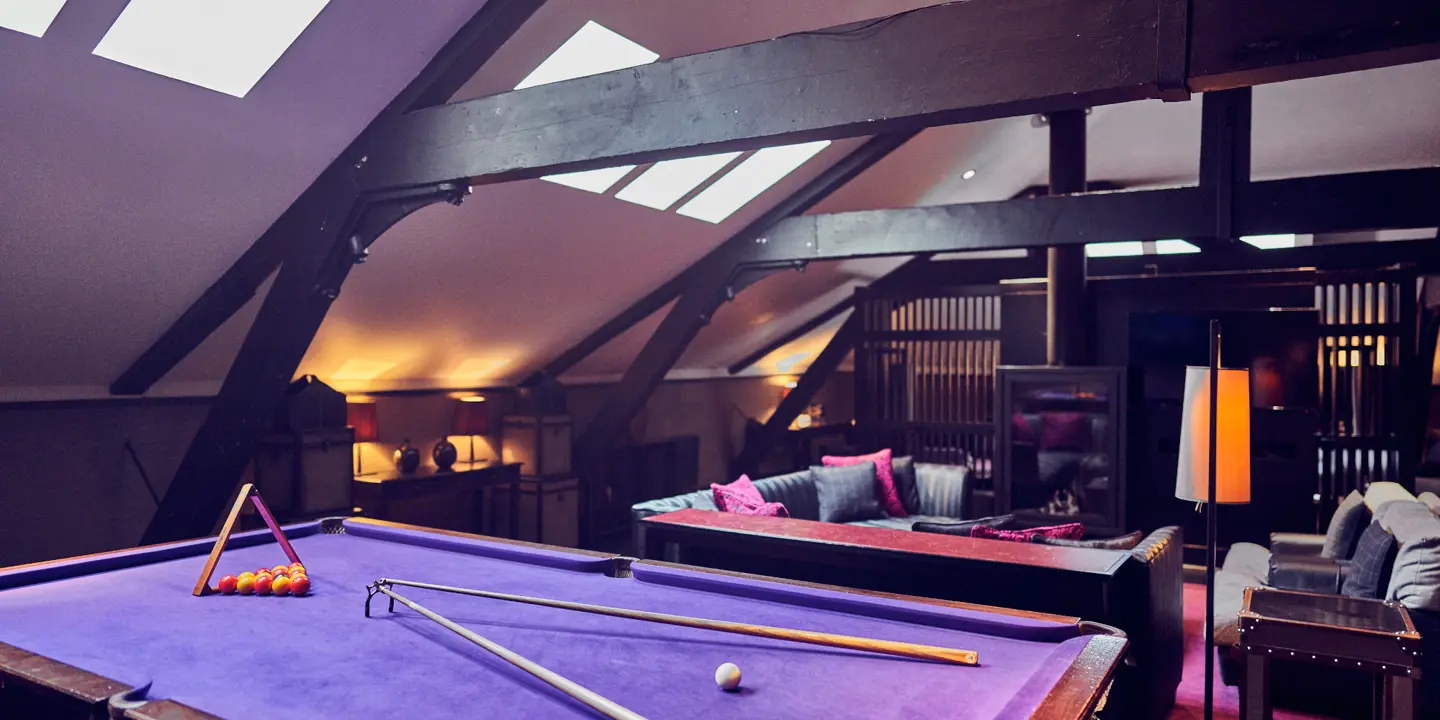 A darkly decorated room with a purple pool table and sofa.