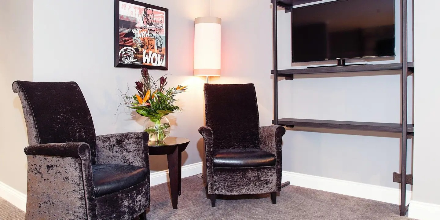 Two chairs and a flat screen TV in a corner of a room.