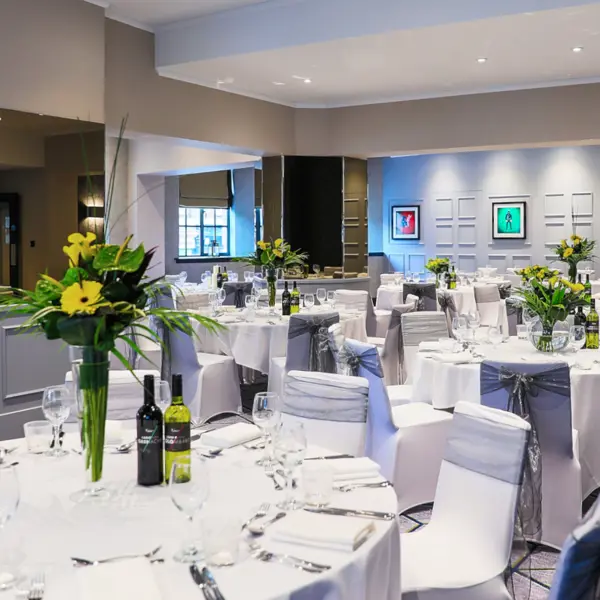 An elegantly arranged banquet room with pristine white tables and chairs.