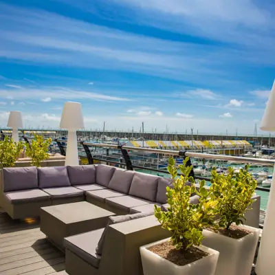 A wooden deck balcony overlooking Brighton Marina, complete with cushioned seating, and feature lighting.