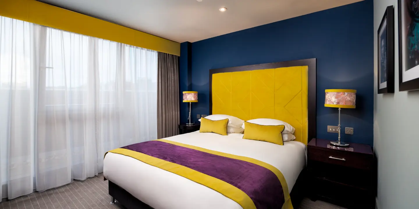 A bedroom featuring a sleek black headboard with tartan print and a desk.