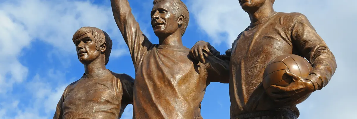 Statue of three men holding a ball.