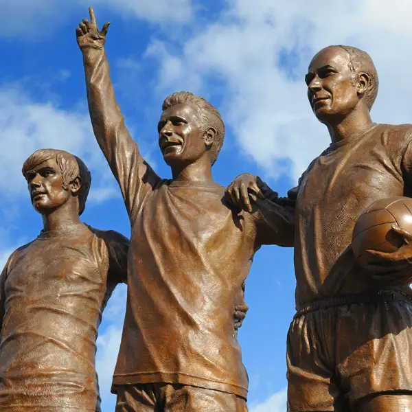 Statue of three men holding a ball.