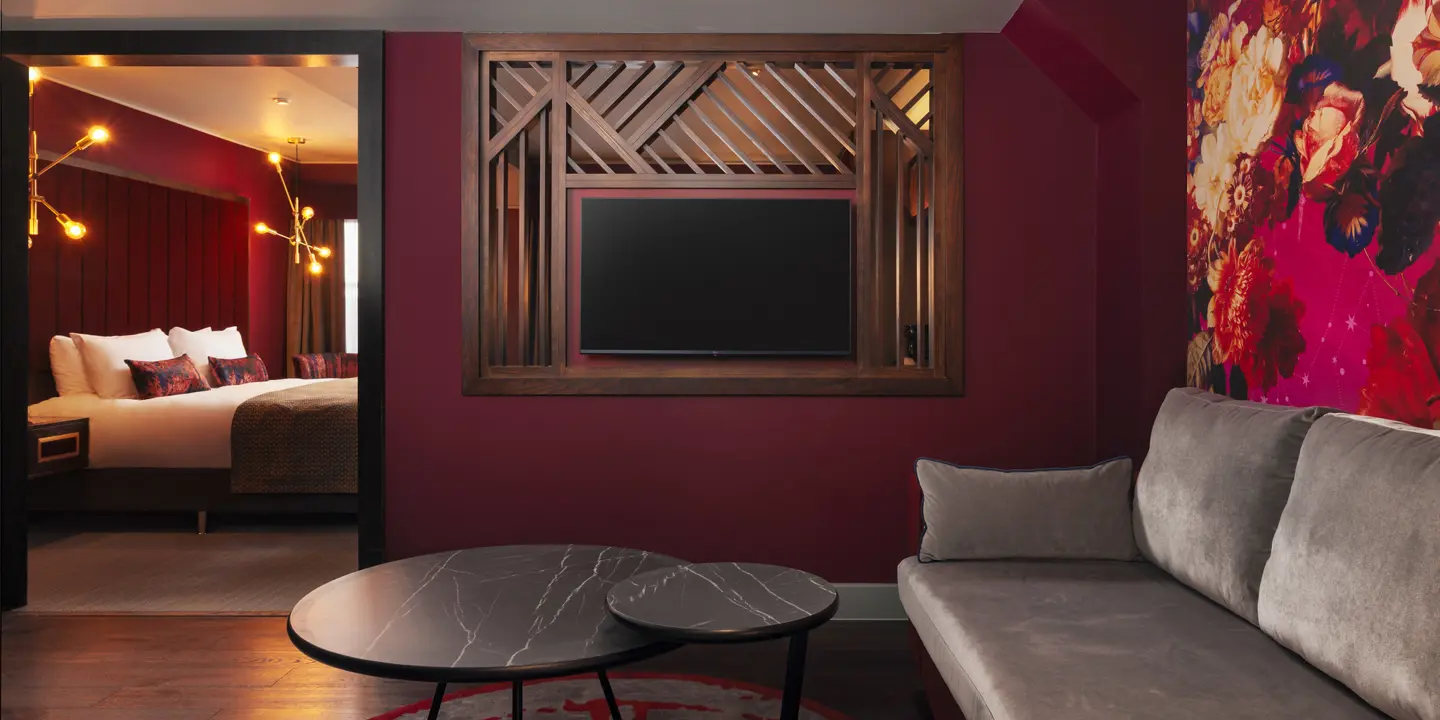 A spacious room featuring a comfortable bed, couch, coffee table and wall-mounted TV