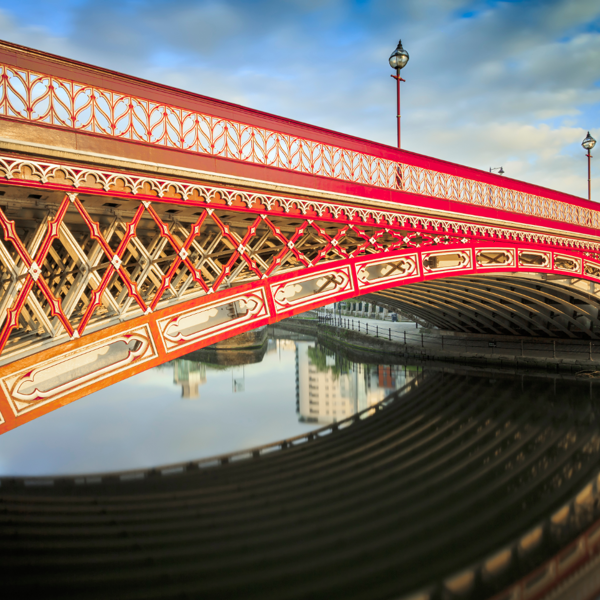Red bridge spanning across a serene body of water.