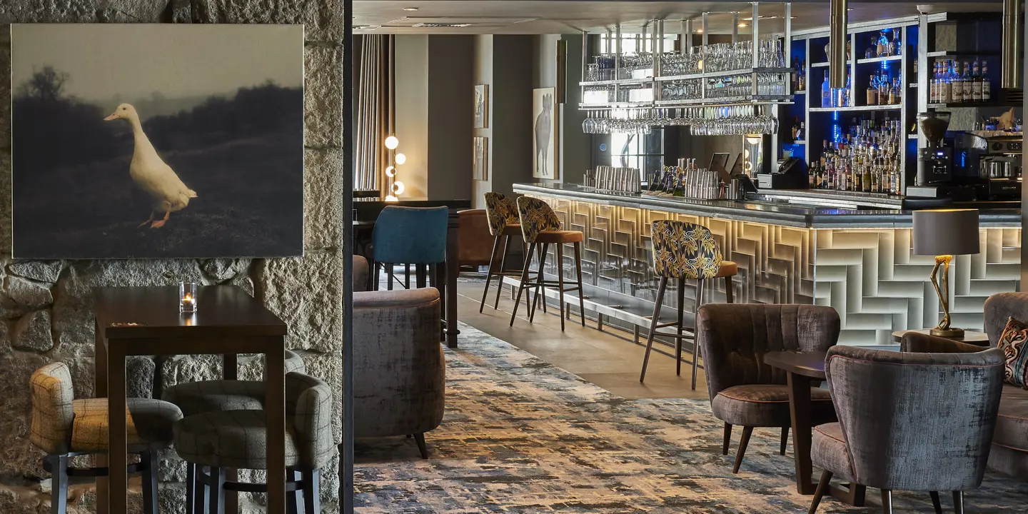 A view of the bar and seating area in Malmaison Aberdeen. Blue and white carpets feature, along with a painting of a white duck.