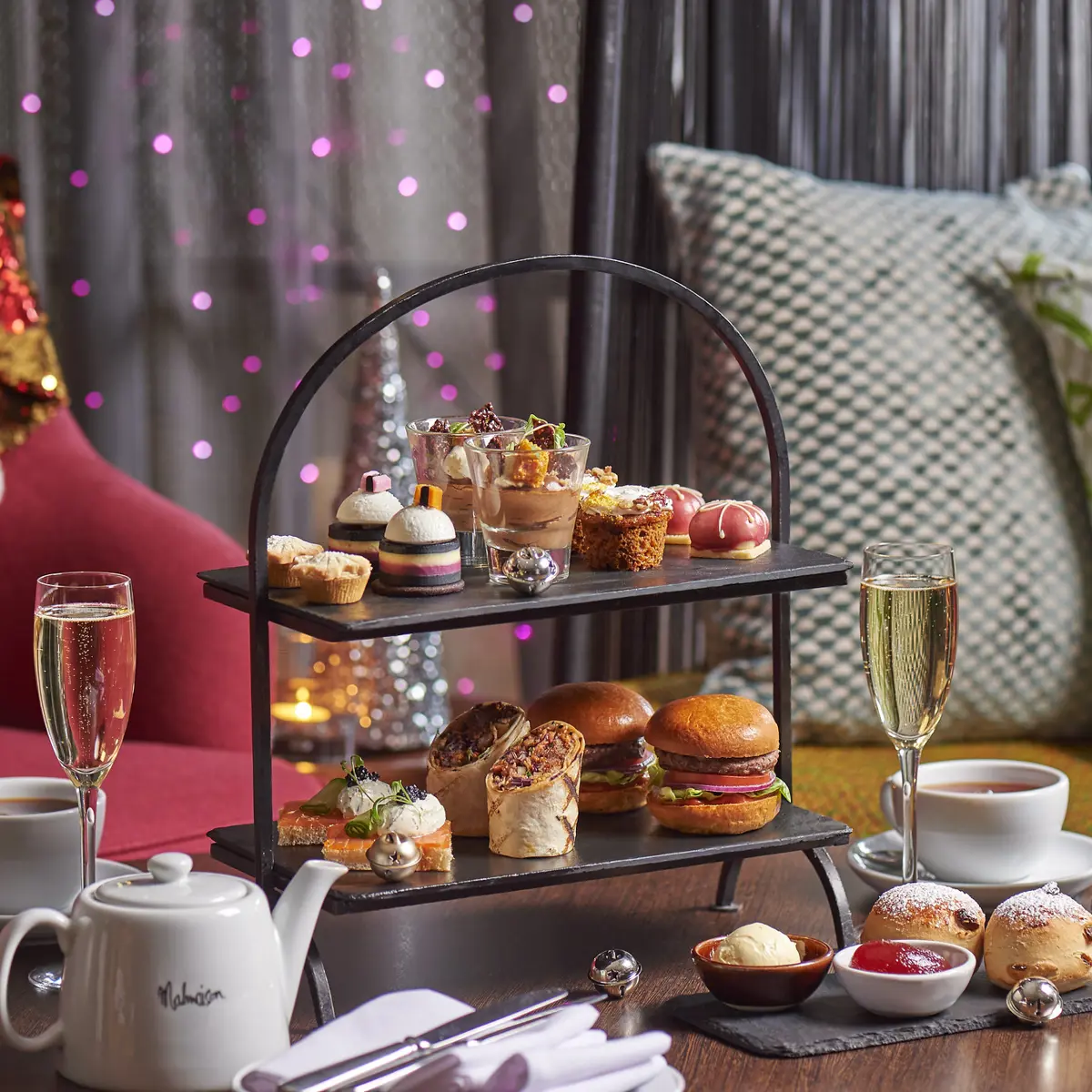 A table displaying a tray of appetizing food accompanied by a glass of fine wine and Christmas decorations in the background.