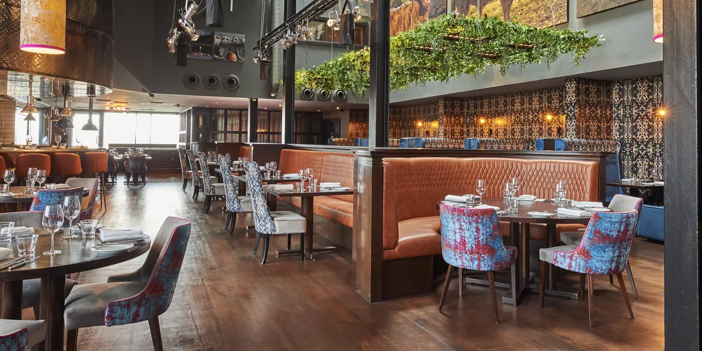 Malmaison Aberdeen Grill restaurant featuring booth seating, feature art on the walls, and overhead lighting rigs.