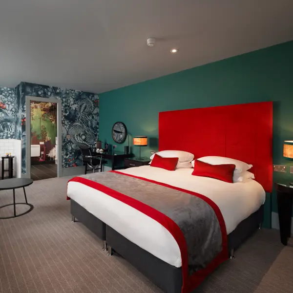 Spacious hotel room featuring a generously-sized bed with a tartan headboard.